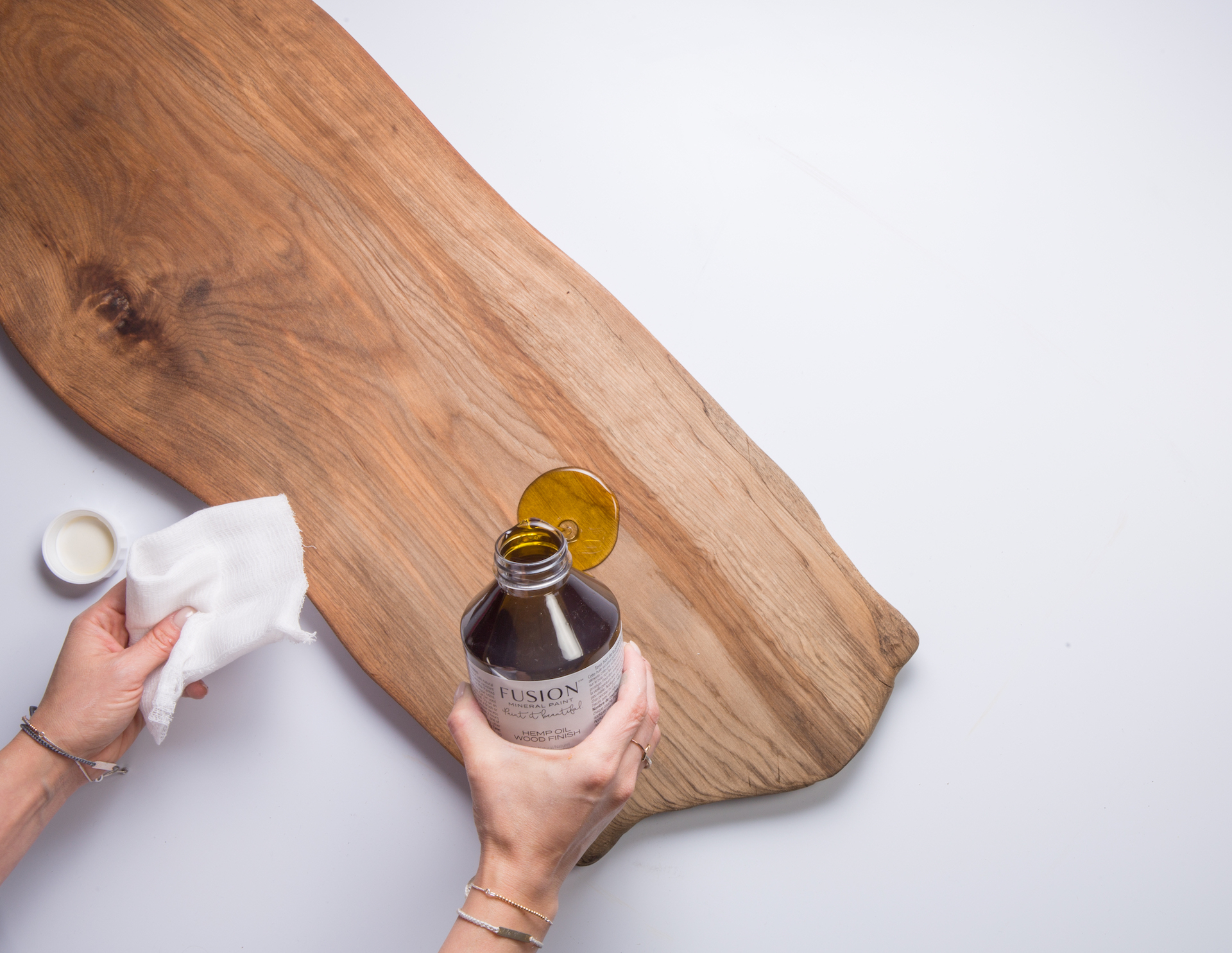 Fusion Hemp Oil being wiped onto a raw wood chopping board.