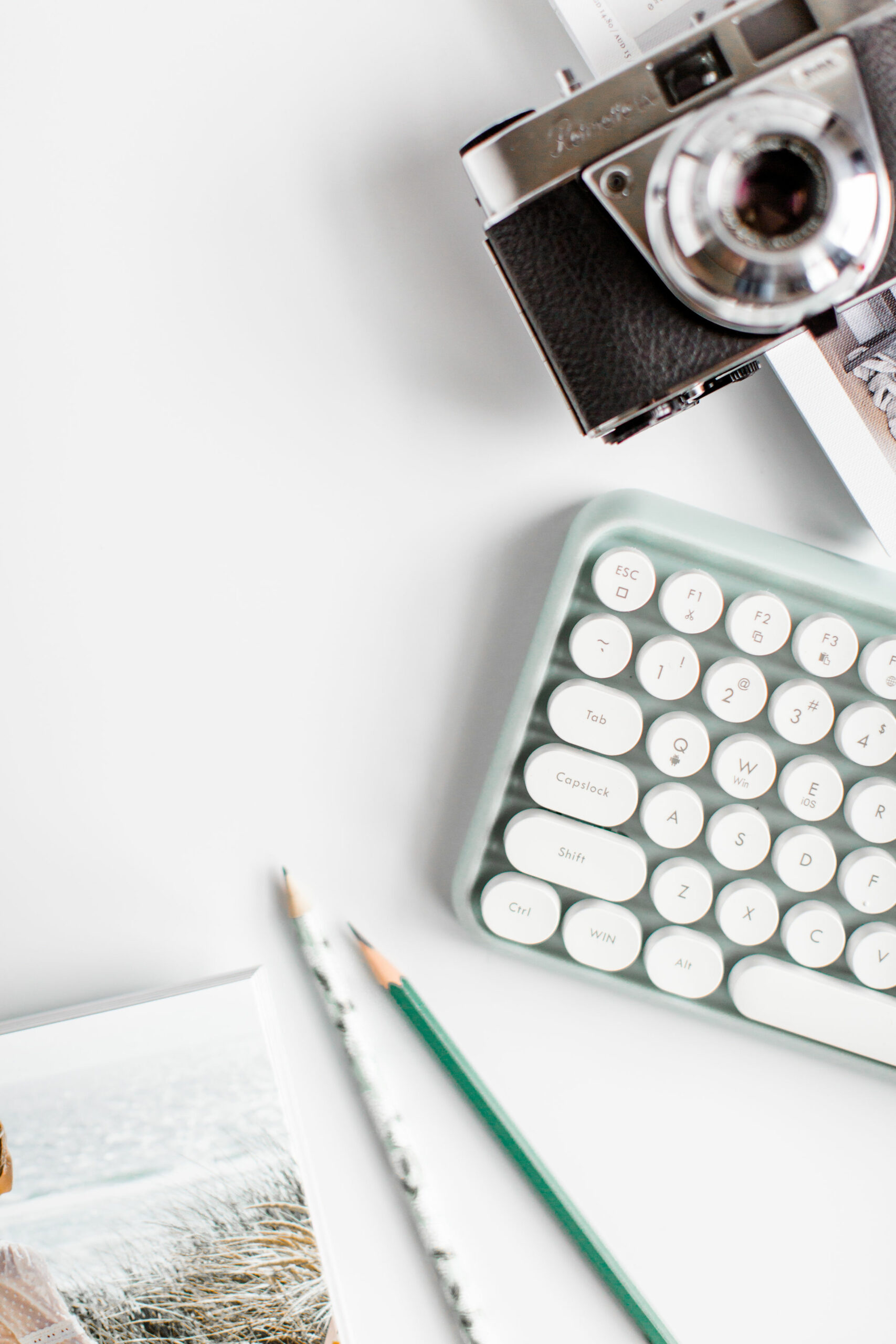 Bright modern flatlay featuring a camera and a white keyboard.